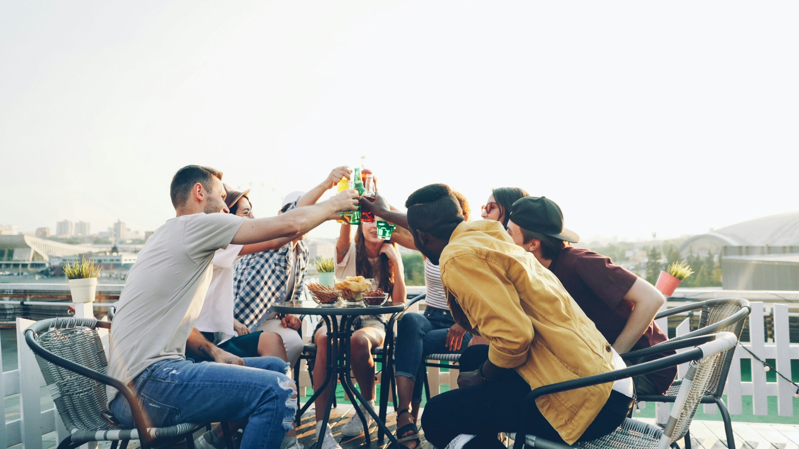 Grupo de amigos brindando com bebidas num terraço ao entardecer